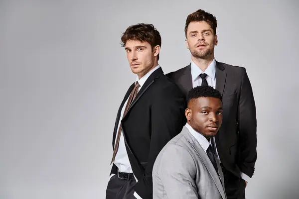 Beaux jeunes modèles masculins multiculturels en tenue décontractée d'affaires posant sur fond gris — Photo de stock