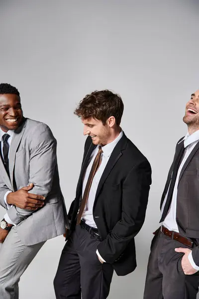 Attraente allegro multiculturale modelli maschili in abiti intelligenti sorridente sinceramente su sfondo grigio — Foto stock