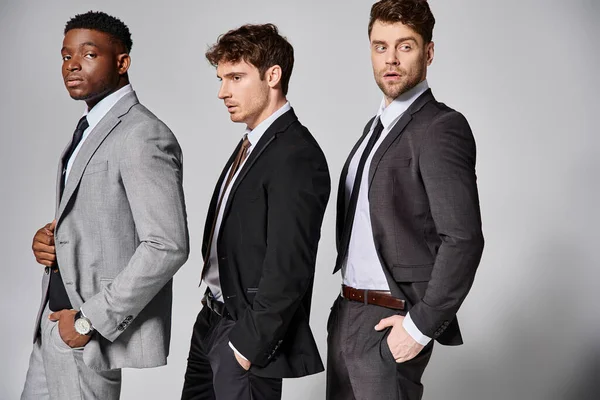 Attractive stylish multicultural male models in business casual attires posing on gray backdrop — Stock Photo