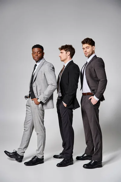 Handsome stylish multicultural male models in business casual attires posing on gray backdrop — Stock Photo