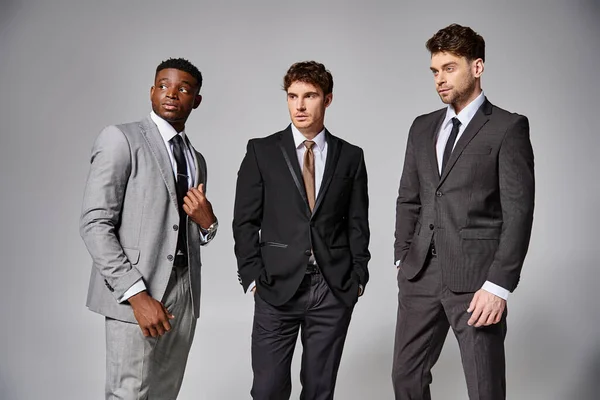 Handsome stylish diverse male models in business elegant smart suits posing on gray backdrop — Stock Photo