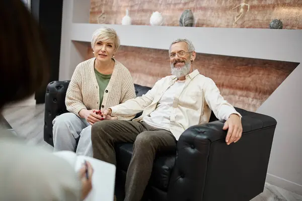 Glückliches Paar mittleren Alters, das zusammen auf der Couch in der Nähe eines Familienberaters sitzt, Beziehungshilfe — Stockfoto
