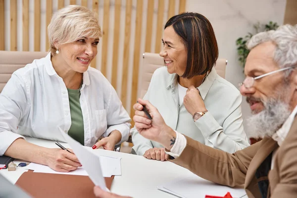 Happy lesbian couple discussing purchase of real estate property near bearded middle aged realtor — Stock Photo