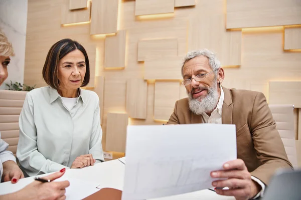 Bearded realtor showing contract to lesbian couple in real estate office, middle aged lgbt family — Stock Photo