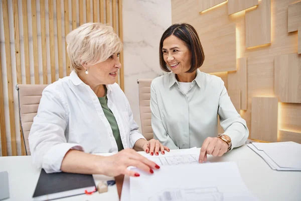 Happy middle aged lesbian couple purchasing real estate property and looking at blueprint — Stock Photo