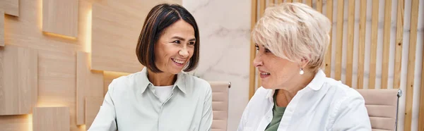 Happy middle aged lesbian couple in smart casual attire smiling in real estate office, banner — Stock Photo