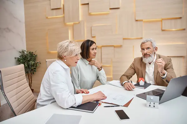 Tattooed realtor discussing mortgage of real estate property with middle aged lesbian couple — Stock Photo