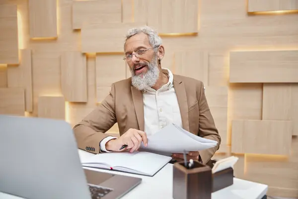 Bearded realtor with tattoo holding contract and having video call on laptop with client — Stock Photo