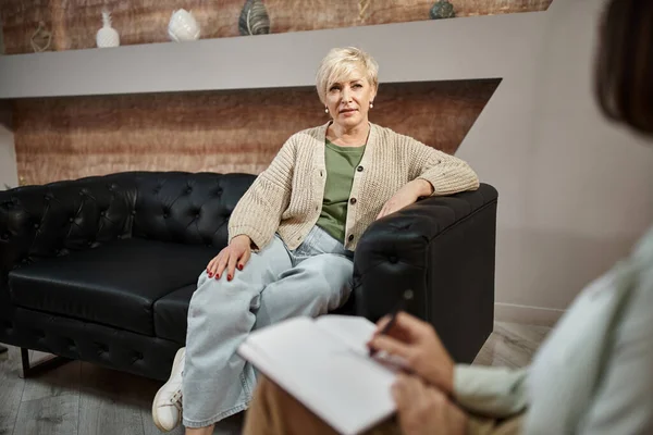 Concentrarsi sulla donna di mezza età seduta sul divano e parlare con la psicologa femminile durante la sessione — Foto stock