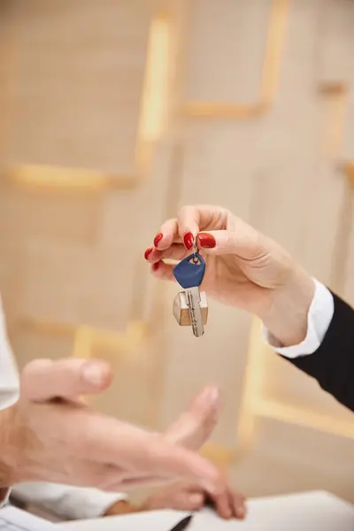 Closed up shot of cropped realtor giving key from new house to client in real estate office — Stock Photo