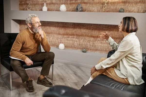 Bärtiger Psychologe mittleren Alters mit Brille spricht während einer Therapiesitzung mit Klientin — Stockfoto