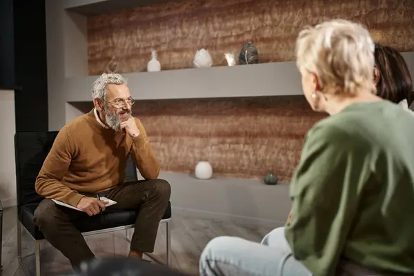 Bearded middle aged psychologist in glasses listening to lesbian couple during therapy session, lgbt — Stock Photo