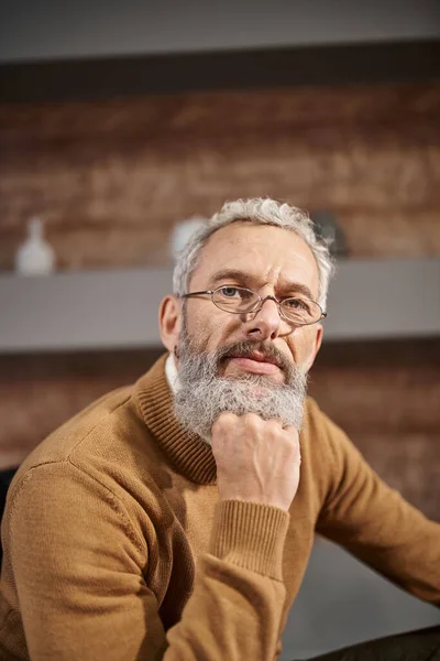 Retrato de belo psicólogo de meia idade em óculos olhando para a câmera durante a sessão de terapia — Fotografia de Stock