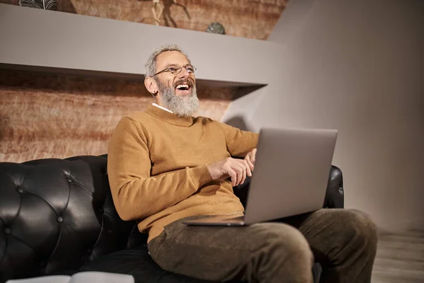 Joyful middle aged psychologist with beard talking during online consultation with client on laptop — Stock Photo