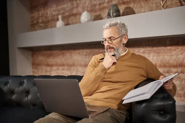 Pensativo psicólogo de mediana edad con barba hablando con el cliente durante la consulta en línea en el ordenador portátil - foto de stock