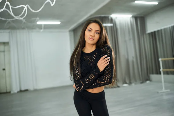 Charming long-haired african american woman in black crop sweater dancing and looking at camera — Stock Photo