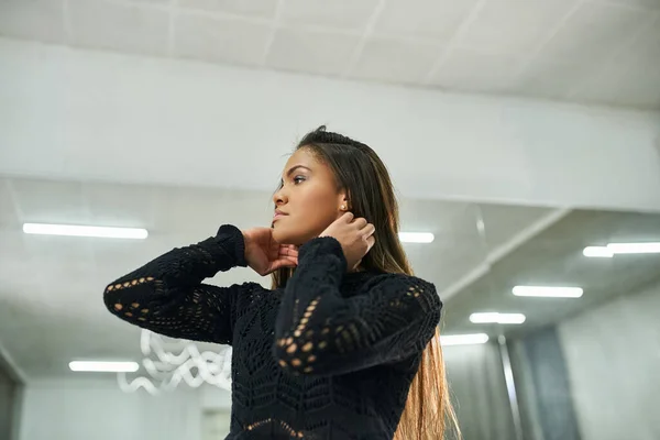 Young african american woman in black attire adjusting long hair in dance studio, choreography — Stock Photo