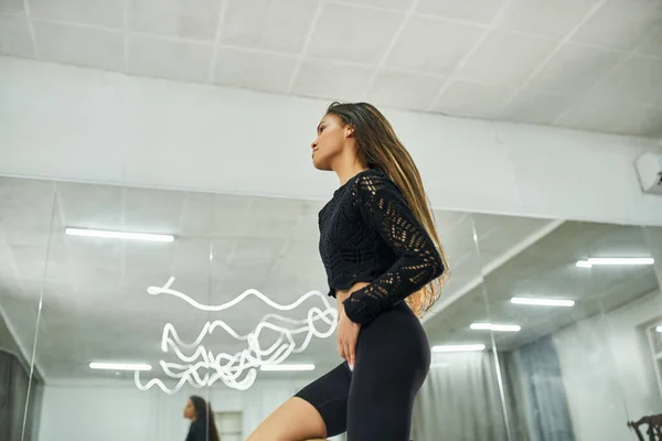 Anmutige und dynamische afrikanisch-amerikanische Frau in schwarzer Kleidung tanzt im Studio, moderne Choreographie — Stockfoto
