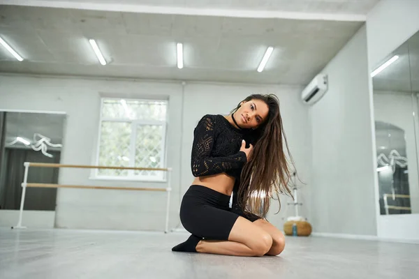 Beautiful african american woman in black attire rehearsing dance on floor in spacious studio — Stock Photo