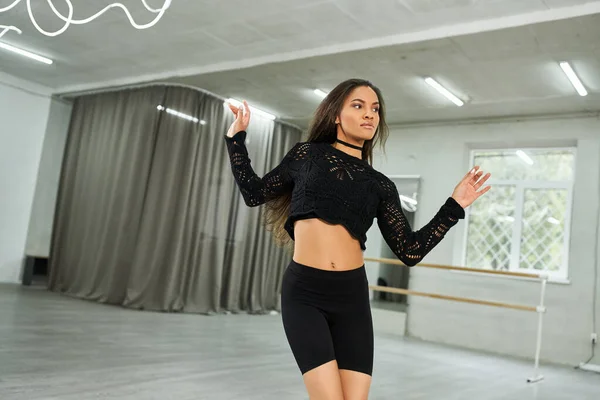 Graceful long-haired african american dancer in black attire rehearsing in dance studio, creativity — Stock Photo