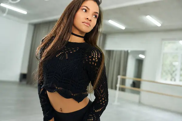 Professional long-haired african american dancer in black attire rehearsing in modern dance studio — Stock Photo