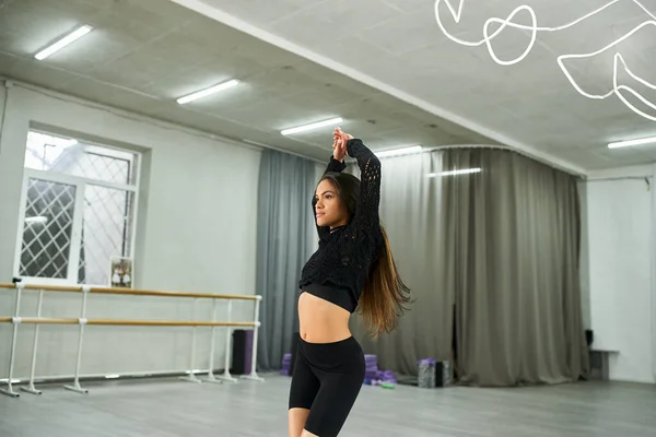 Expressive african american dancer in black attire rehearsing in dance studio, rhythmic movement — Stock Photo