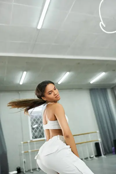 Jovem dançarina afro-americana de cabelos longos em sportswear branco ensaiando no estúdio de dança moderna — Fotografia de Stock