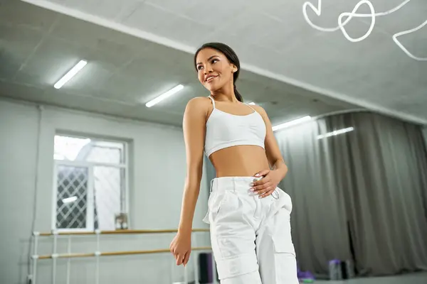Smiling african american female dancer in white sports top and pants training in modern studio — Stock Photo