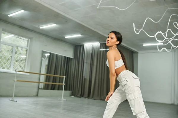 Graciosa dançarina afro-americana em sportswear branco ensaiando e treinando em estúdio moderno — Fotografia de Stock