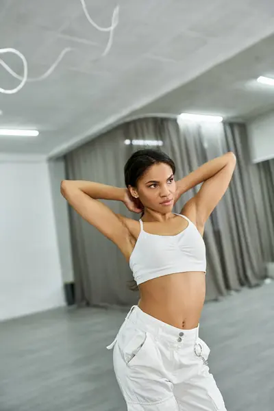 Jovem dançarina afro-americana flexível em sportswear branco ensaiando e treinando no salão de dança — Fotografia de Stock
