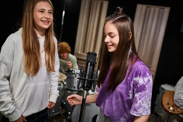 Vier entzückende fröhliche Teenager singen und spielen verschiedene Instrumente in Studio, Musikgruppe — Stockfoto