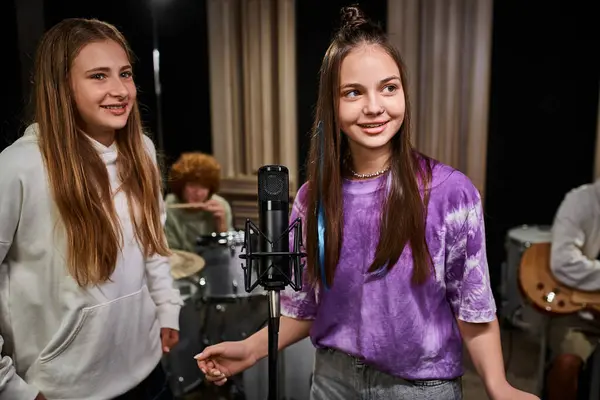 Adolescentes muito alegres em trajes casuais cantando e tocando instrumentos em estúdio, grupo musical — Fotografia de Stock