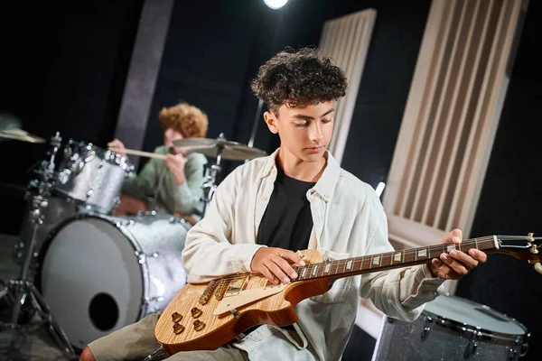 Fokussierte talentierte Teenager in lässiger Kleidung, die im Studio Gitarre und Schlagzeug spielen, Musikgruppe — Stockfoto