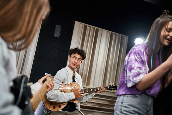 Alegres adolescentes bonitos em trajes cotidianos cantando e tocando vários instrumentos em estúdio — Fotografia de Stock