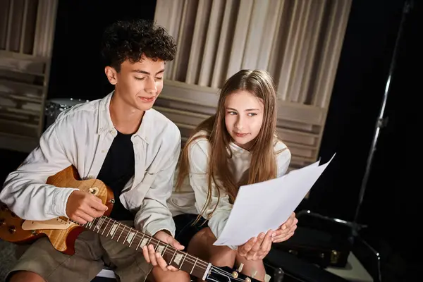Allegri musicisti adolescenti di talento in abiti di tutti i giorni in posa con la chitarra e guardando i testi — Foto stock
