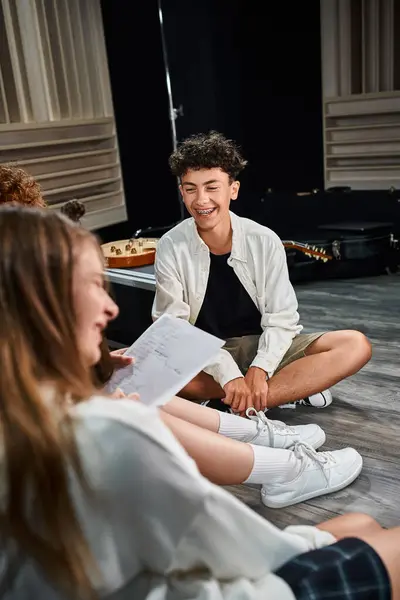 Adorable jolly teenage boy with braces smiling happily at his blurred cheerful friend in studio — Stock Photo