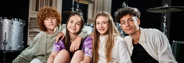 Happy teenagers in casual outfits sitting in studio and looking at camera, musical group, banner — Stock Photo