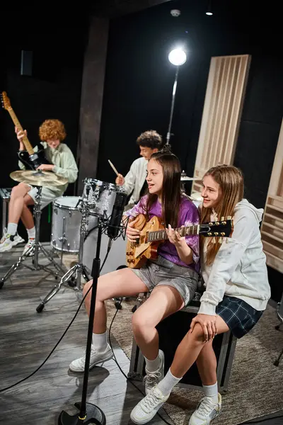 Se concentrar em meninas adolescentes com guitarra cantando enquanto seus amigos turvos tocando instrumentos — Fotografia de Stock