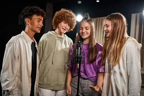 Jolly adorable teens in everyday cozy outfits singing into microphone together, musical group — Stock Photo