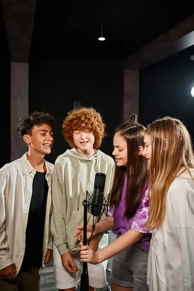 Joyeux jeunes garçons et filles talentueux chantant ensemble et souriant en studio, groupe musical — Photo de stock