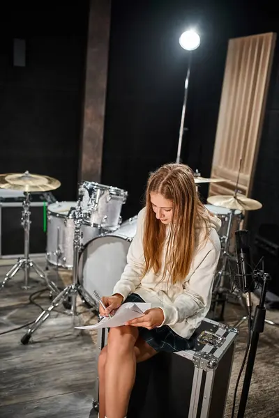 Приваблива блондинка-підліток в повсякденному вбранні пише лірику перед мікрофоном в студії — стокове фото