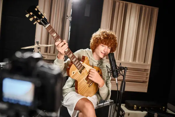 Alegre lindo adolescente en traje diario tocando su guitarra y cantando en el micrófono - foto de stock