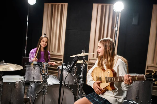 Duas adolescentes muito talentosas em roupas casuais tocando guitarra e bateria, grupo musical — Fotografia de Stock