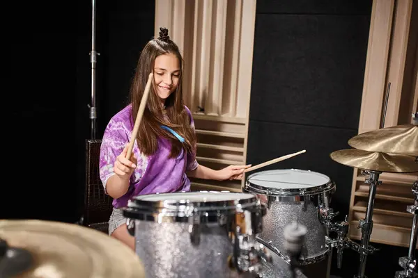 Gut aussehende brünette Teenager-Mädchen in lebendiger Freizeitkleidung, die im Musikstudio Schlagzeug spielt — Stockfoto