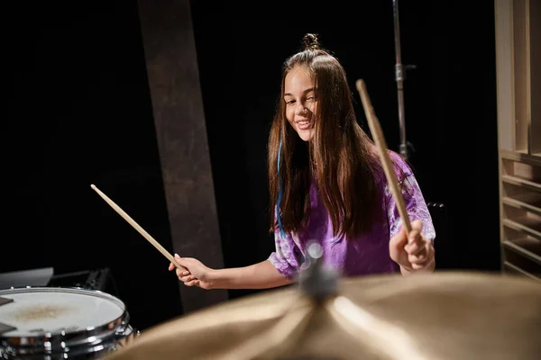 Joyeux talentueux adorable adolescente en tenue audacieuse quotidienne jouer de la batterie tout en studio — Photo de stock