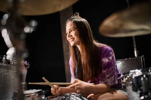 Fröhliches entzückendes Teenager-Mädchen in lässigem Outfit, das im Musikstudio fröhlich Schlagzeug spielt — Stockfoto