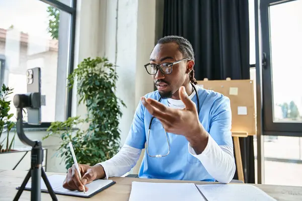 Thoughtful handsome african american doctor taking notes while consulting by phone, telemedicine — Stock Photo