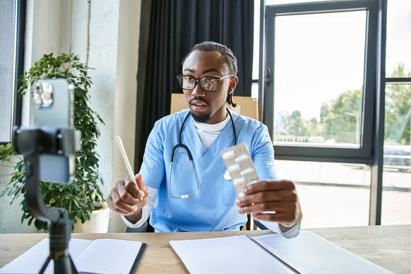 Сфокусированный красивый африканский американский врач держит таблетки и делает заметки во время консультации по телефону — стоковое фото