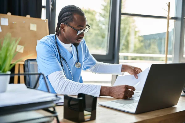 Красивый задумчивый африканский американский врач, глядя на свои заметки во время онлайн-консультации, телездравоохранения — стоковое фото