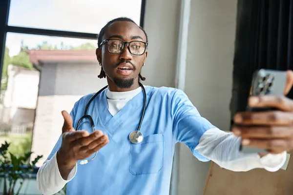 Médecin afro-américain concentré avec des lunettes consulter quelqu'un par téléphone mobile, télémédecine — Photo de stock